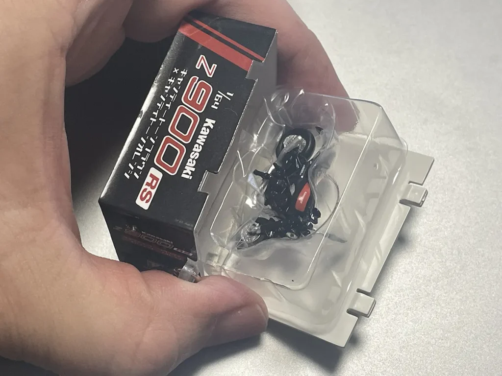 拆開背蓋後，即可取出收納在塑膠內盒中的模型。由於背蓋僅靠卡榫固定，若要當作吊飾隨身攜帶，建議使用膠帶稍加補強固定。