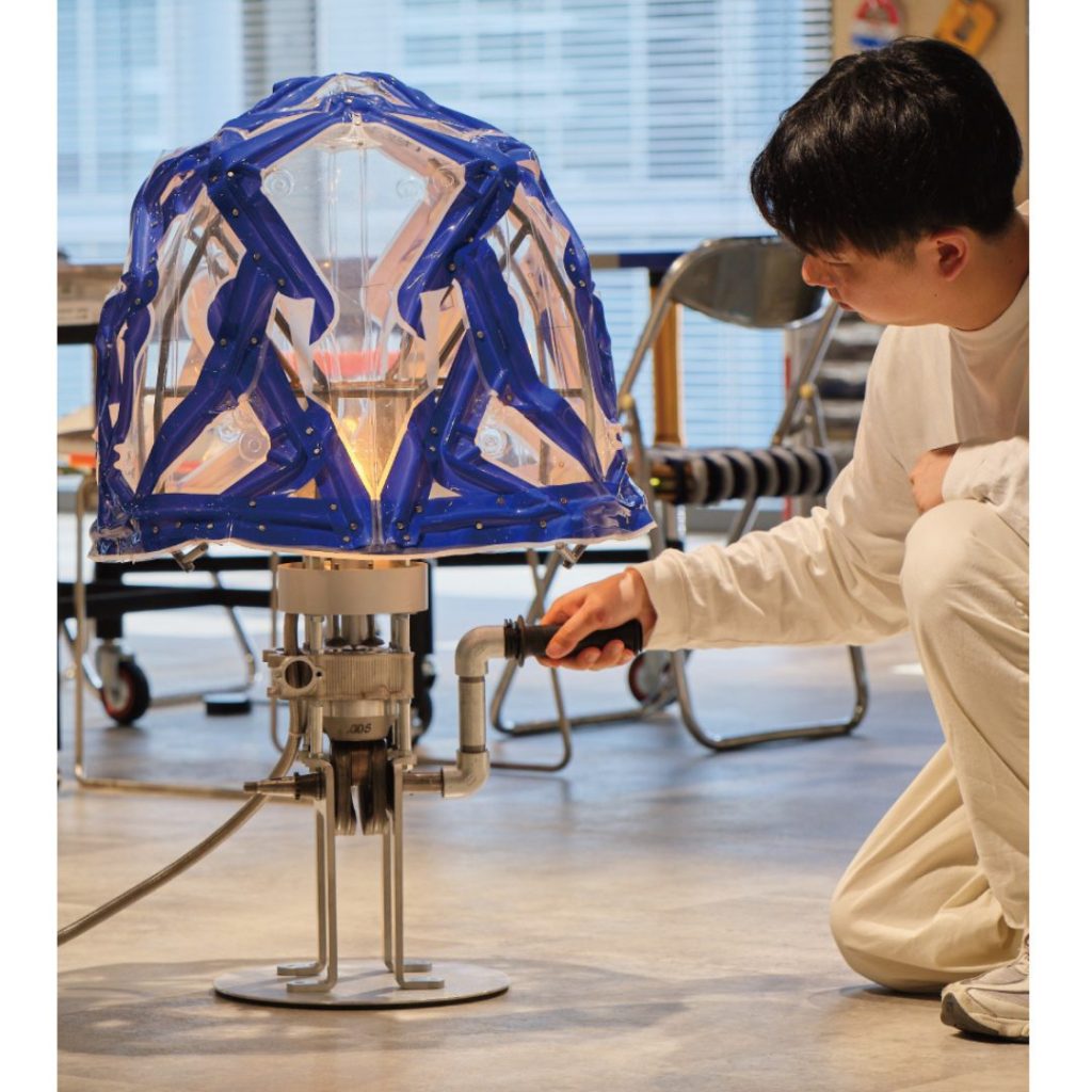 8mm 厚鋁合金一體成型底座搭載真實四行程引擎機構。手動旋轉手把可連動齒輪與活塞運動，LED 燈會配合實際引擎的壓縮與爆炸時機點亮。